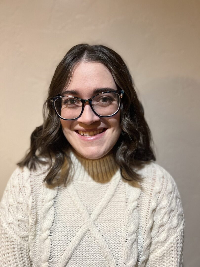 A woman with glasses and a sweater on.