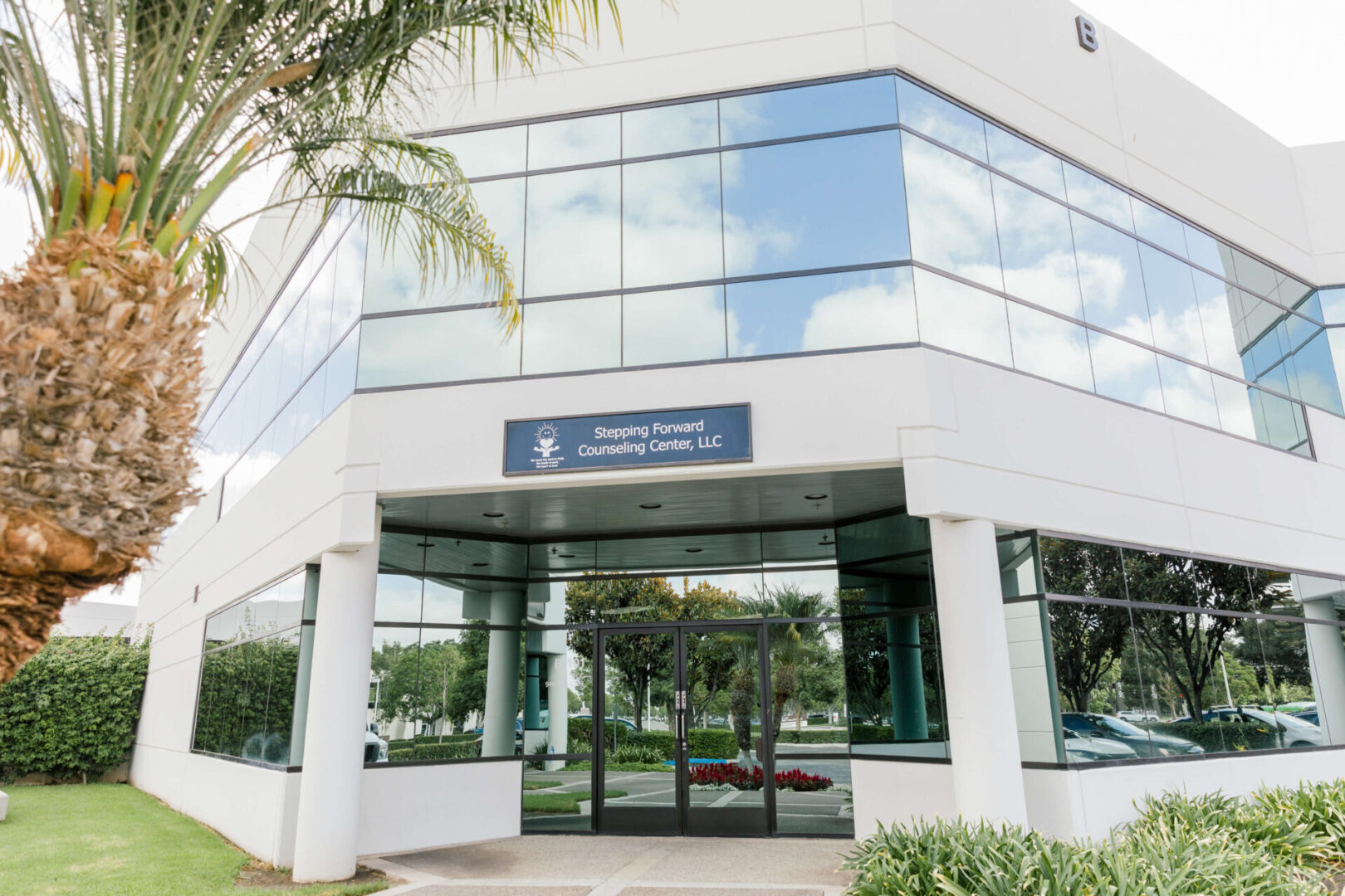 A building with glass windows and palm trees in the background.