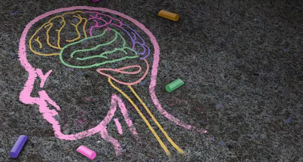 A chalk drawing of a human head with crayons.