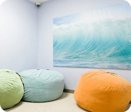 Three bean bags in a room with a painting on the wall.