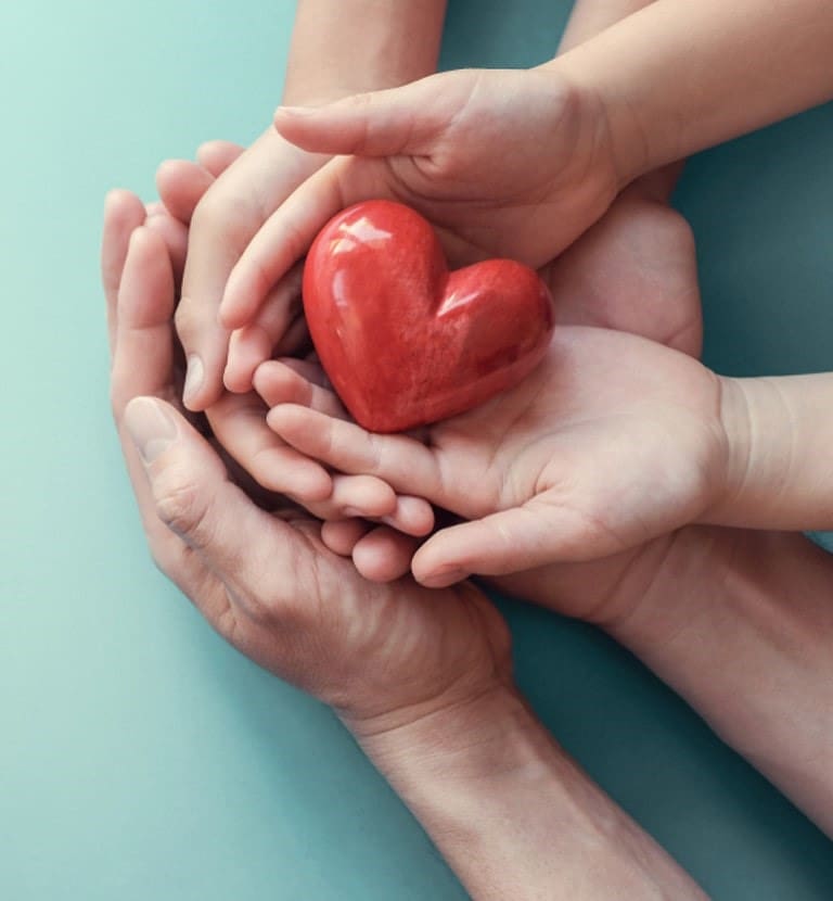 A group of people holding hands with a heart.