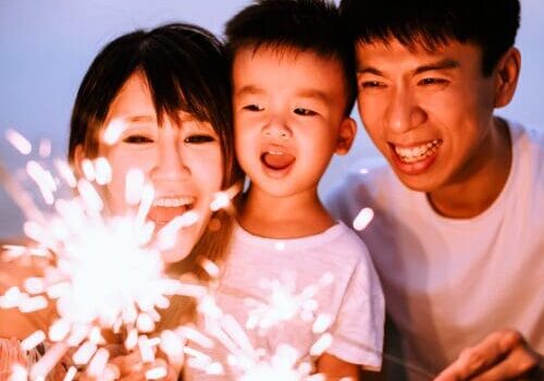 A man and woman holding sparklers with a child.