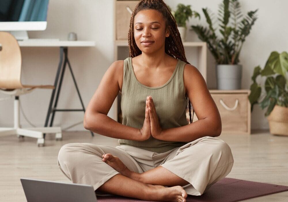 A woman sitting on the ground in front of a laptop.