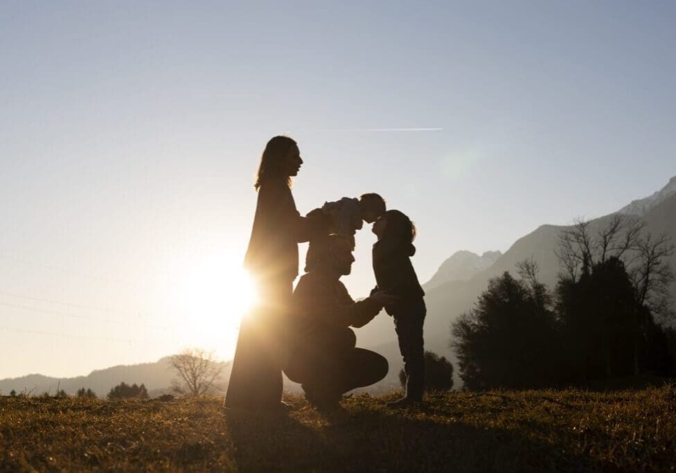 A woman and two children are standing in the grass.