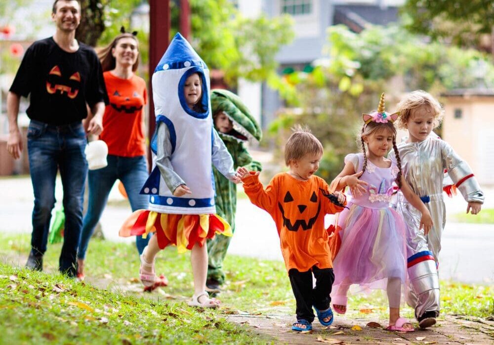 A group of children in costumes walking down the street.